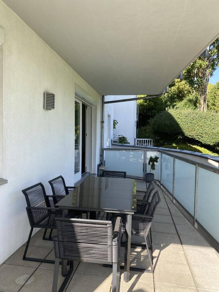 Geräumiger Balkon mit modernen Outdoor-Möbeln und Blick auf die umliegende grüne Landschaft.