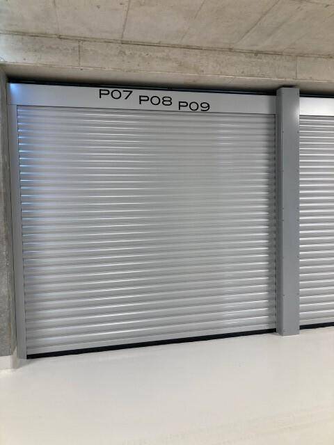 Geschlossene Garagentore in einer Tiefgarage mit nummerierten Stellplätzen und hellem Boden.