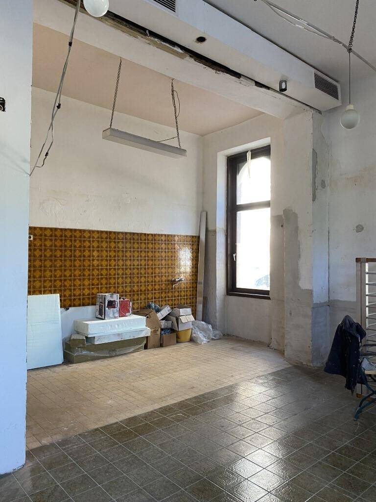 Leerer Raum in Renovierung mit Fliesenboden und Fenster, zeigt den aktuellen Zustand des Objekts.