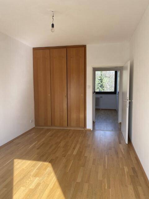 Geräumiges Schlafzimmer mit großem Einbauschrank, Parkettboden und viel Tageslicht.