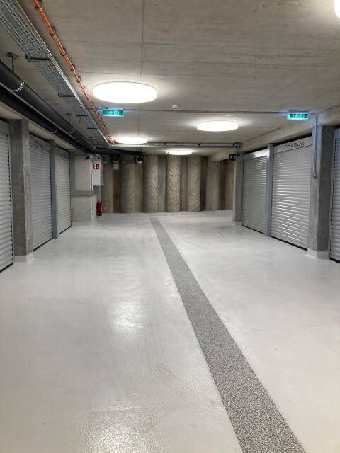 Geräumige Tiefgarage mit Rolltoren und moderner Beleuchtung, bietet sichere Parkmöglichkeiten.