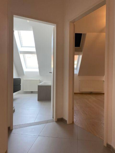 Blick vom Flur in ein helles Badezimmer und einen weiteren Raum mit Dachschrägen und Dachfenstern.