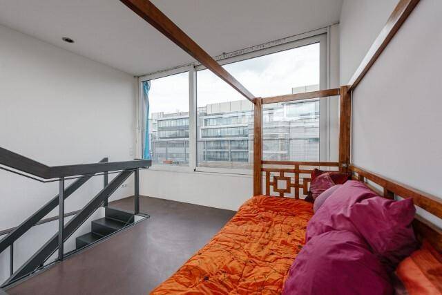 Schlafzimmer mit Himmelbett und großen Fenstern, die viel Tageslicht hereinlassen und Stadtblick bieten.