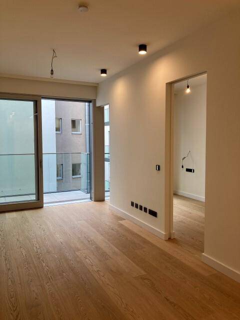 Geräumiges Zimmer mit Parkettboden und Schiebetür zum Balkon, bietet viel Tageslicht.