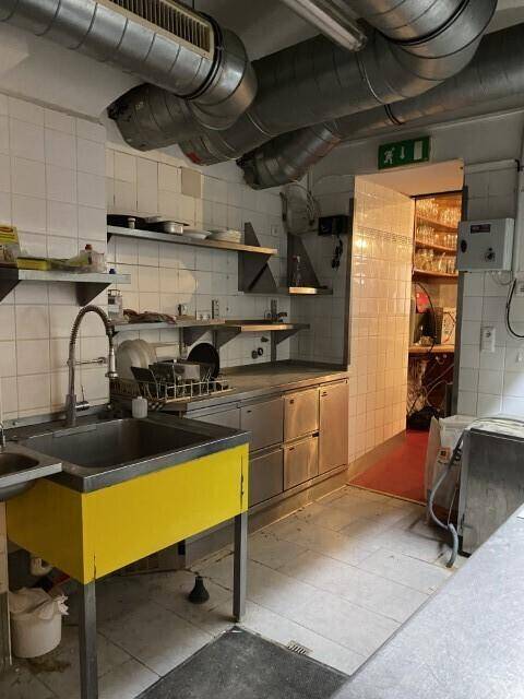 Gewerbliche Küche mit mehreren Spülbecken, Edelstahlmöbeln und einem Durchgang zu einem weiteren Bereich, effizient gestaltet.