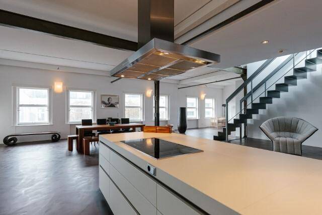 Offene Küche mit Kochinsel und Blick auf den Essbereich und die Treppe in diesem Loft-Apartment.