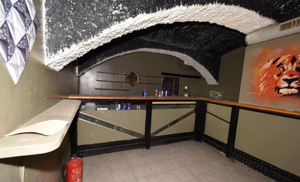 Barbühne mit Theke, einem Löwen-Wandgemälde und einer gewölbten, strukturierten Decke, renovierungsbedürftig.