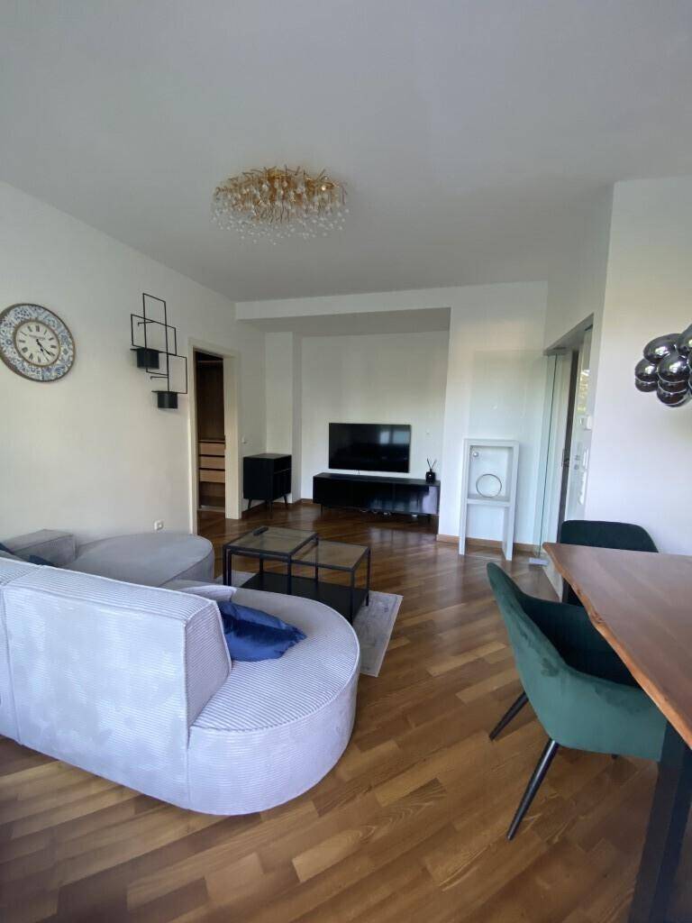 Geräumiger Wohn- und Essbereich mit Holzboden, Fernseher und modernem Mobiliar.