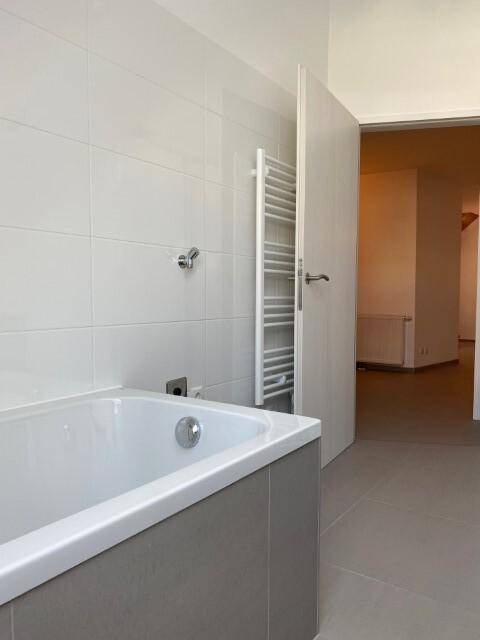 Badewanne und beheizter Handtuchhalter in einem modernen, gefliesten Badezimmer.