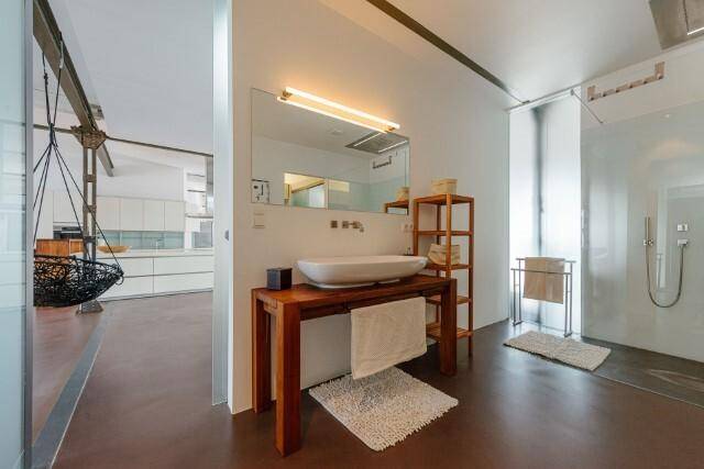 Modernes Badezimmer mit Aufsatzwaschbecken, Holzkonsole und Blick in den offenen Wohnbereich.