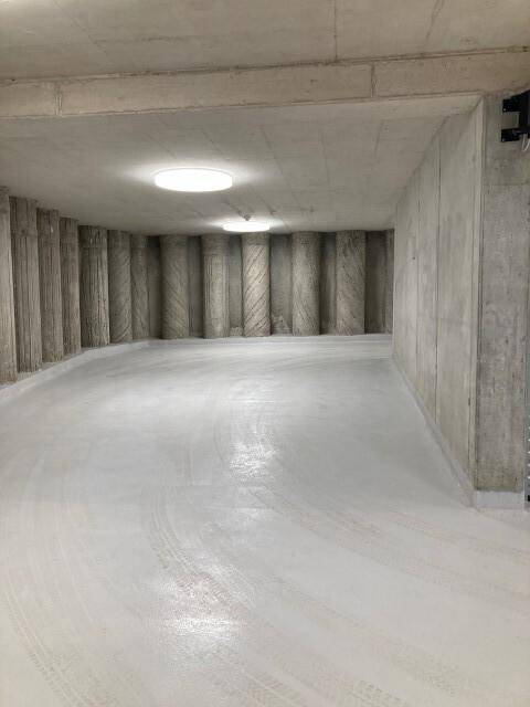 Helle Tiefgarage mit Betonwänden und glattem Boden, ausreichend Platz für Fahrzeuge.