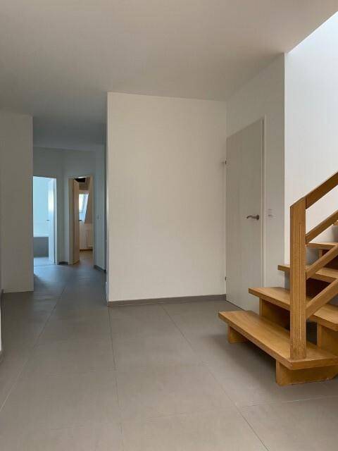 Geräumiger Flur mit Fliesenboden und einer eleganten Holztreppe, die in die obere Etage führt.