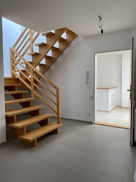 Elegante Holztreppe in einem hellen Flur mit Fliesenboden, die die Etagen verbindet.