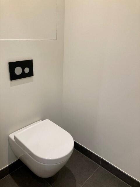Modernes Wand-WC mit minimalistischem Design und dunkler Spülplatte, sauber und funktional.