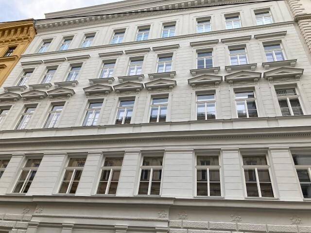 Klassische Fassade eines Altbaus mit vielen Fenstern und dekorativen Elementen, gut erhalten.