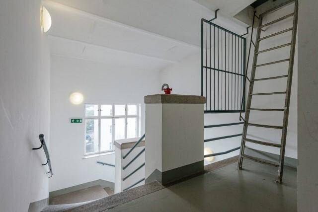 Treppenhaus mit robusten Stufen und Geländer, das zu den oberen Etagen führt.