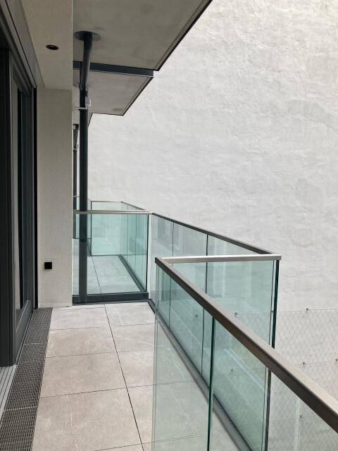 Heller Balkon mit elegantem Glasgeländer und Fliesenboden, ideal für entspannte Stunden im Freien.