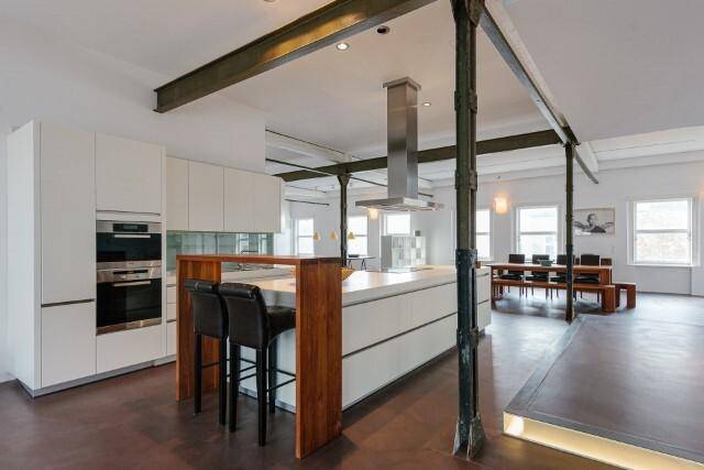 Stilvolle Küche mit weißer Front, Kochinsel und Frühstücksbar in einem weitläufigen Loft.