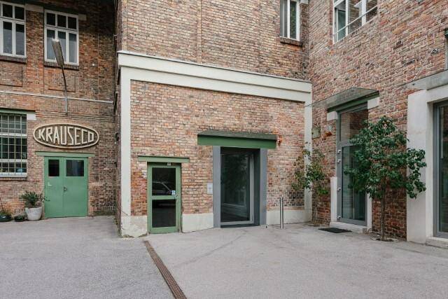 Historisches Backsteingebäude mit modernen Eingängen und gepflastertem Innenhof.