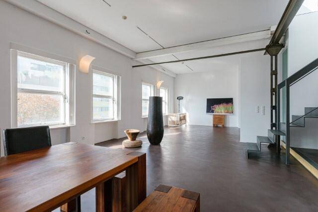 Heller Essbereich in einem weitläufigen Loft mit hohen Decken und großen Fenstern.