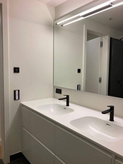 Modernes Badezimmer mit Doppelwaschbecken, großem Spiegel und schwarzen Armaturen.