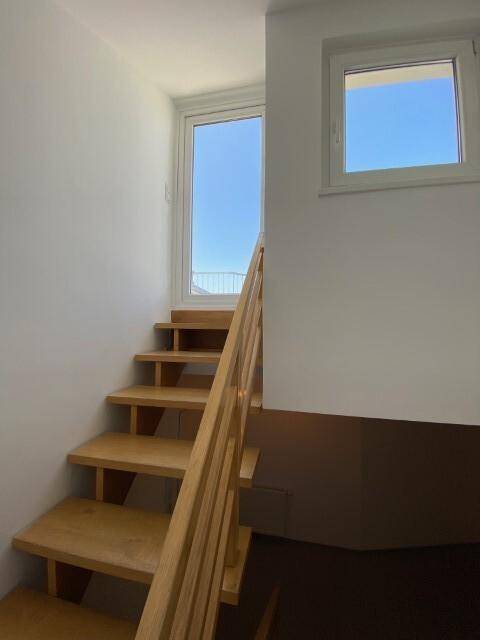 Holztreppe führt zu einer Tür und einem Fenster, die Zugang zum Außenbereich bieten.