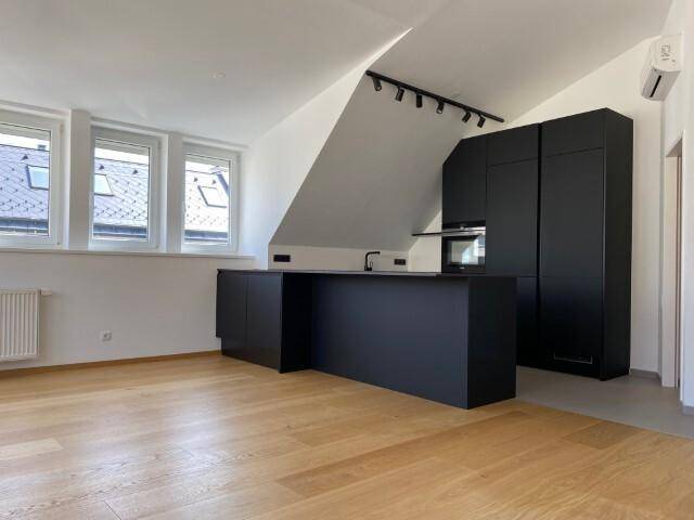 Moderne, offene Küche mit schwarzer Kücheninsel und Einbauschränken unter Dachschrägen.