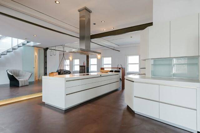 Moderne, minimalistische Küche mit großer Kochinsel und integriertem Dunstabzug in einem hellen Loft.