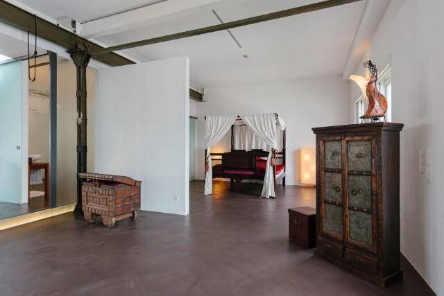 Geräumiges Schlafzimmer mit Himmelbett und antiken Möbeln, angrenzend an einen offenen Bereich.
