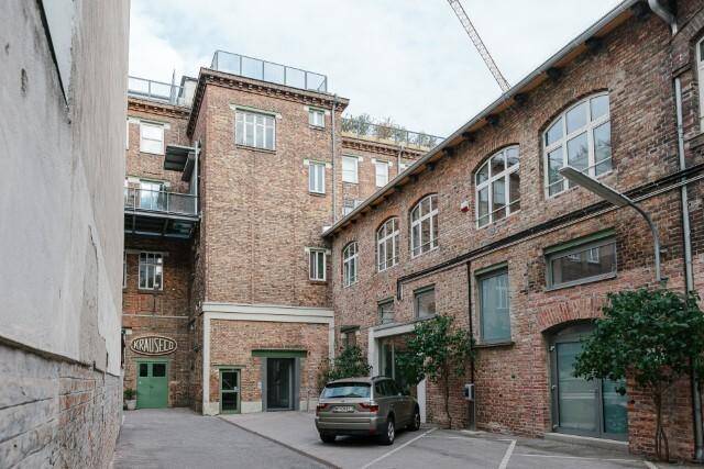 Industrielles Backsteingebäude mit vielen Fenstern und einem geparkten Auto im Innenhof.