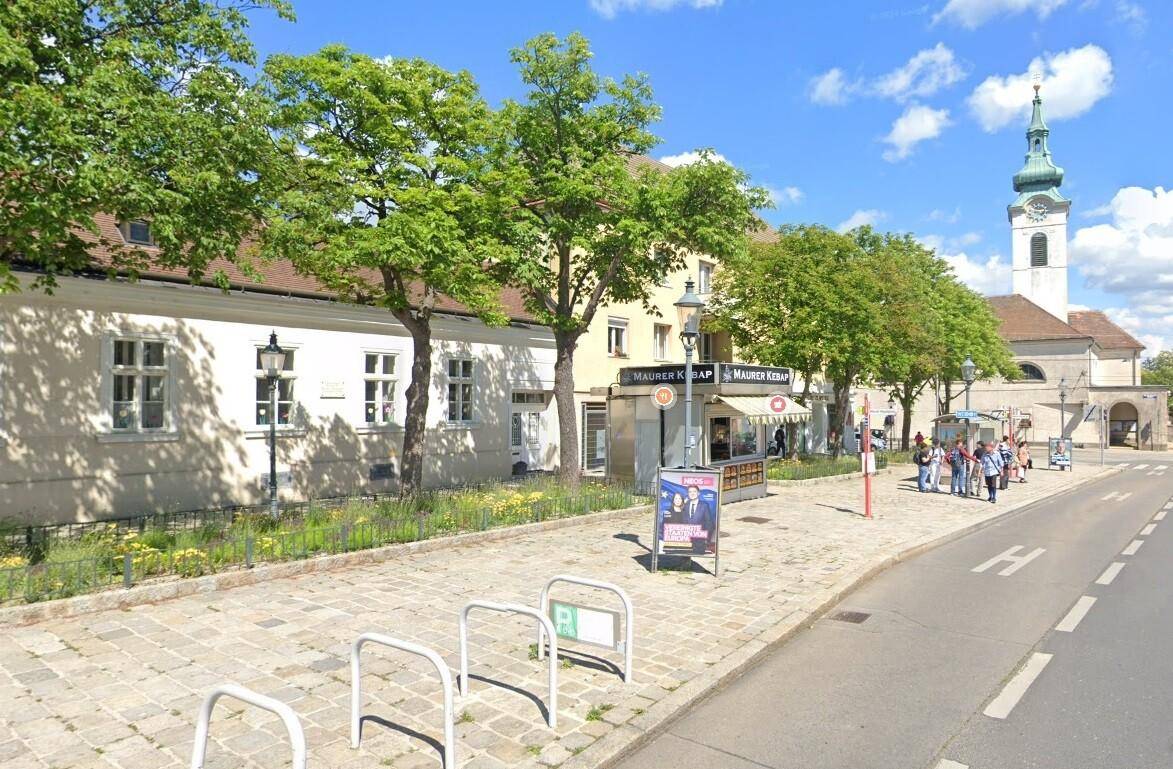 Blick auf eine belebte Straße mit Geschäften, einem Kebab-Stand und einer Kirche im Hintergrund.