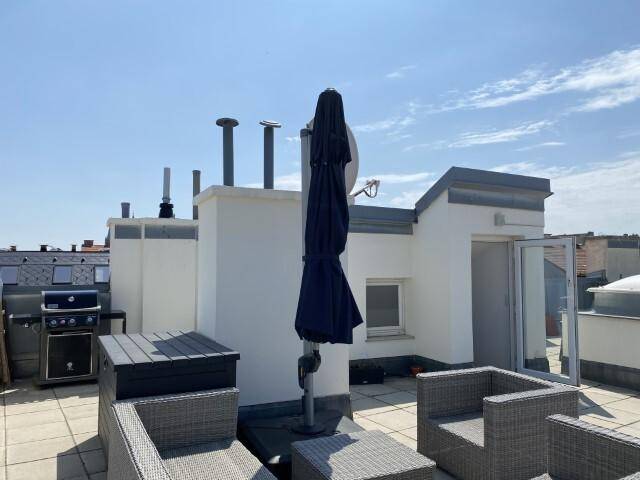 Geräumige Dachterrasse mit Loungemöbeln, Grillbereich und Sonnenschirm.