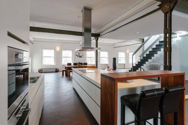 Stilvolle Küche mit Frühstücksbar und Hockern, nahtlos in den offenen Wohnraum integriert.