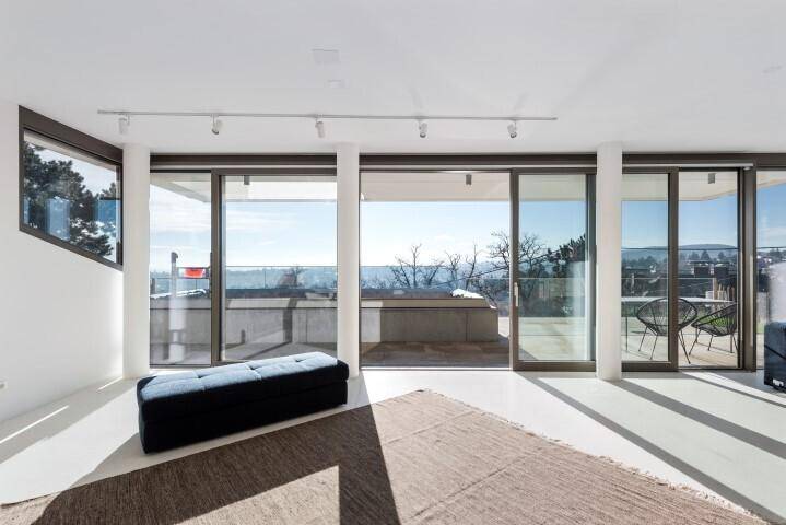Helles Wohnzimmer mit großen Schiebetüren, die auf die Terrasse führen und einen weiten Ausblick bieten.