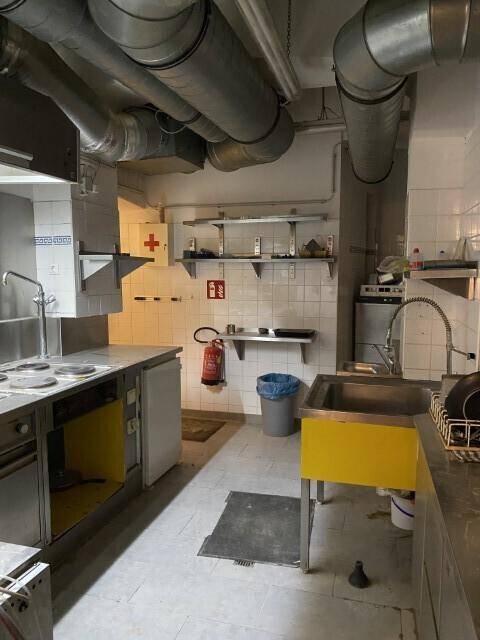Funktionale Gewerbeküche mit Edelstahlspülen, Arbeitsflächen und sichtbaren Lüftungsrohren, ausgestattet für den Restaurantbetrieb.