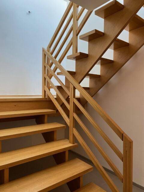 Detailansicht der hochwertigen Holztreppe mit elegantem Geländer und offenen Stufen.