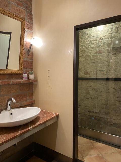 Badezimmer mit einem modernen Aufsatzwaschbecken auf einer Marmorplatte und einer Duschkabine mit Glaswand.