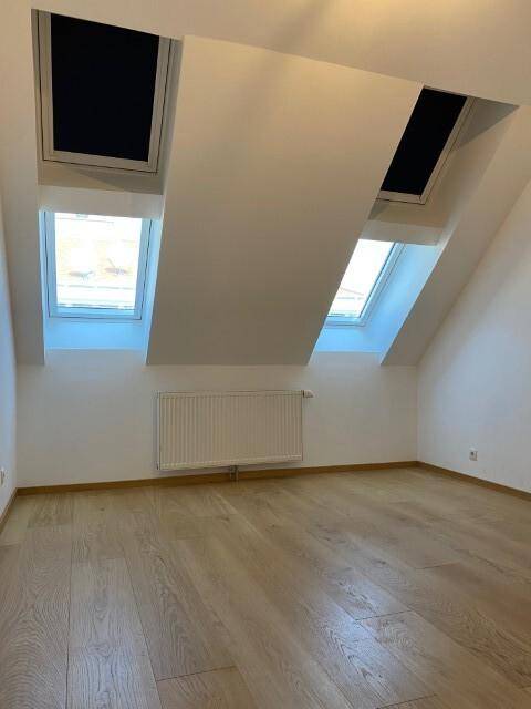 Helles Zimmer mit Dachschrägen, Holzboden und zwei großen Dachfenstern für viel Licht.