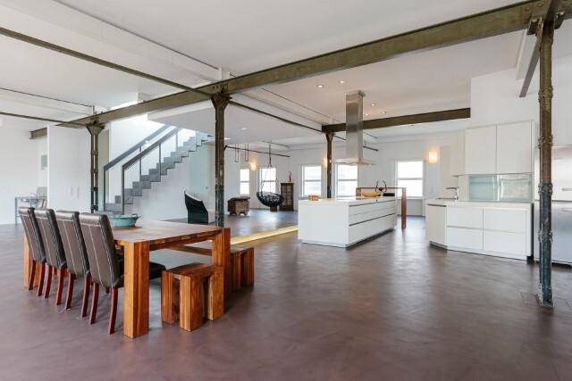 Weitläufiger Loft-Raum mit moderner offener Küche, Essbereich und Treppenzugang.