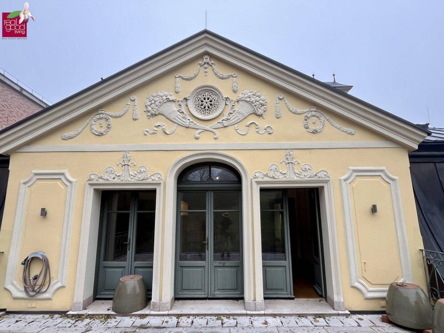Historische Fassade mit aufwendigen Stuckverzierungen und großen Flügeltüren, die den Eingangsbereich schmücken.
