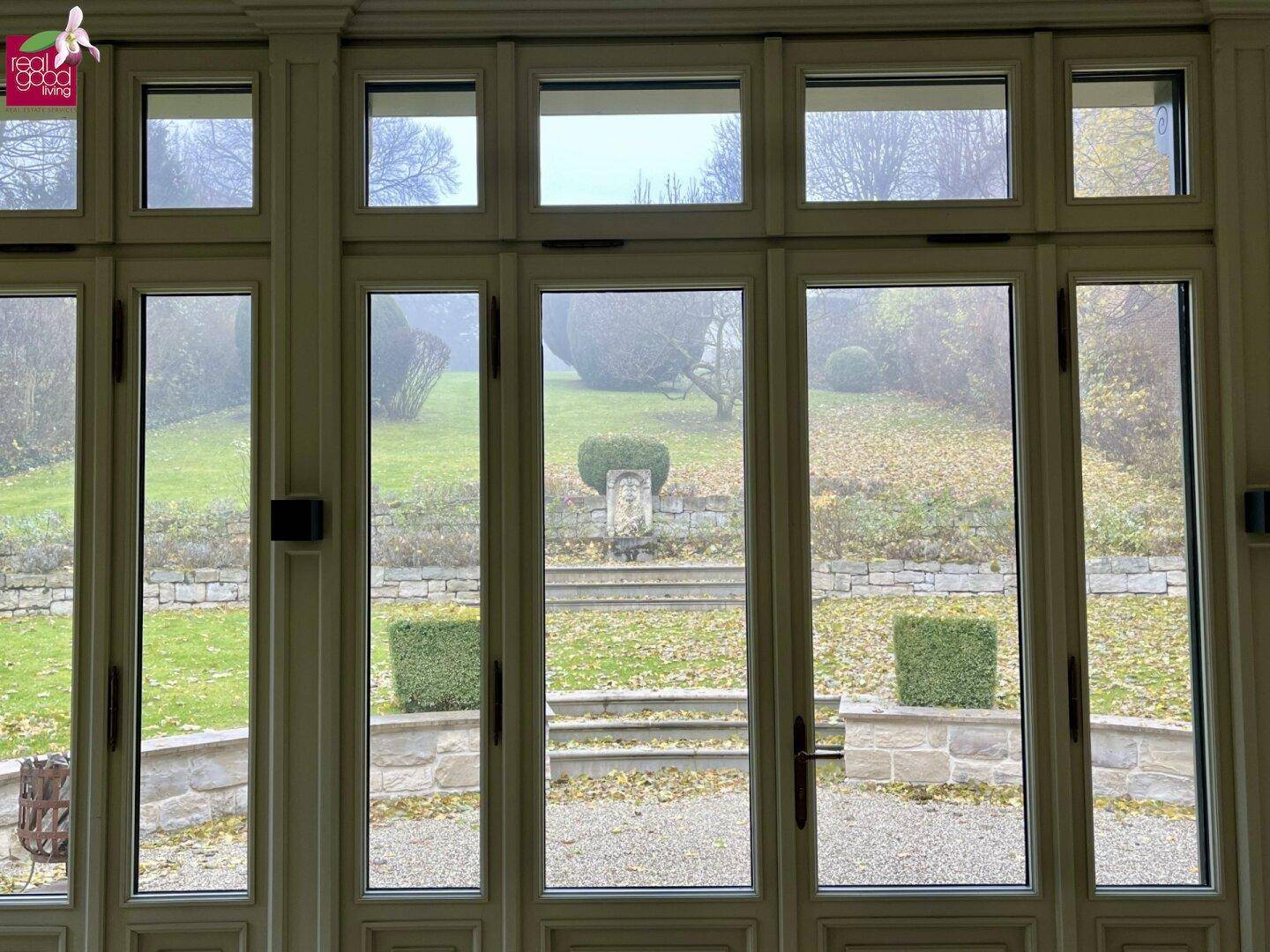 Heller Raum mit großen Fenstern und direktem Blick auf den gepflegten Garten.