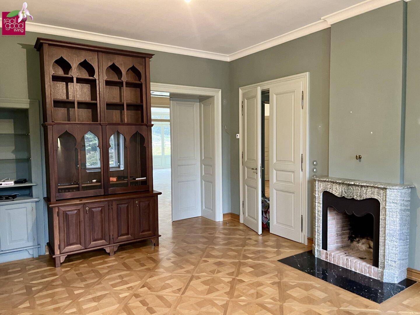 Gemütliches Wohnzimmer mit dekorativem Kamin, Holzboden und traditionellen Möbeln.