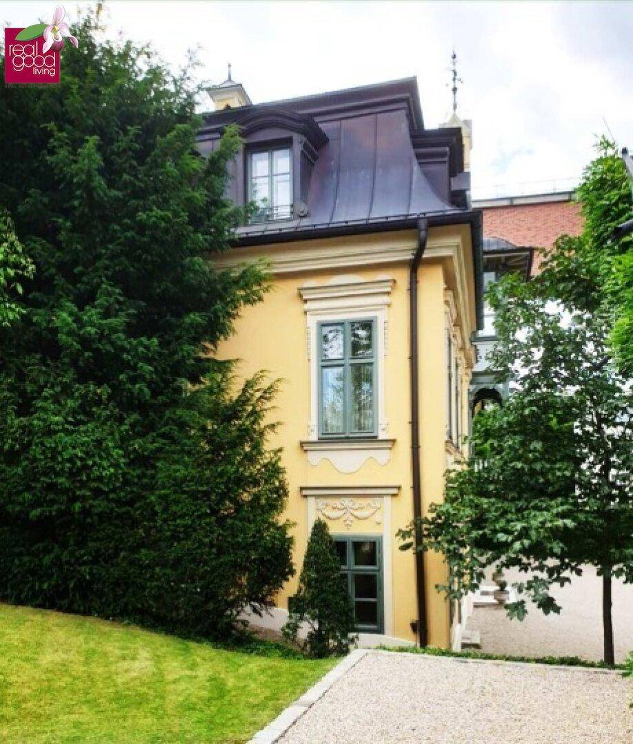 Seitenansicht der Villa mit üppiger Bepflanzung und klassischer Architektur.