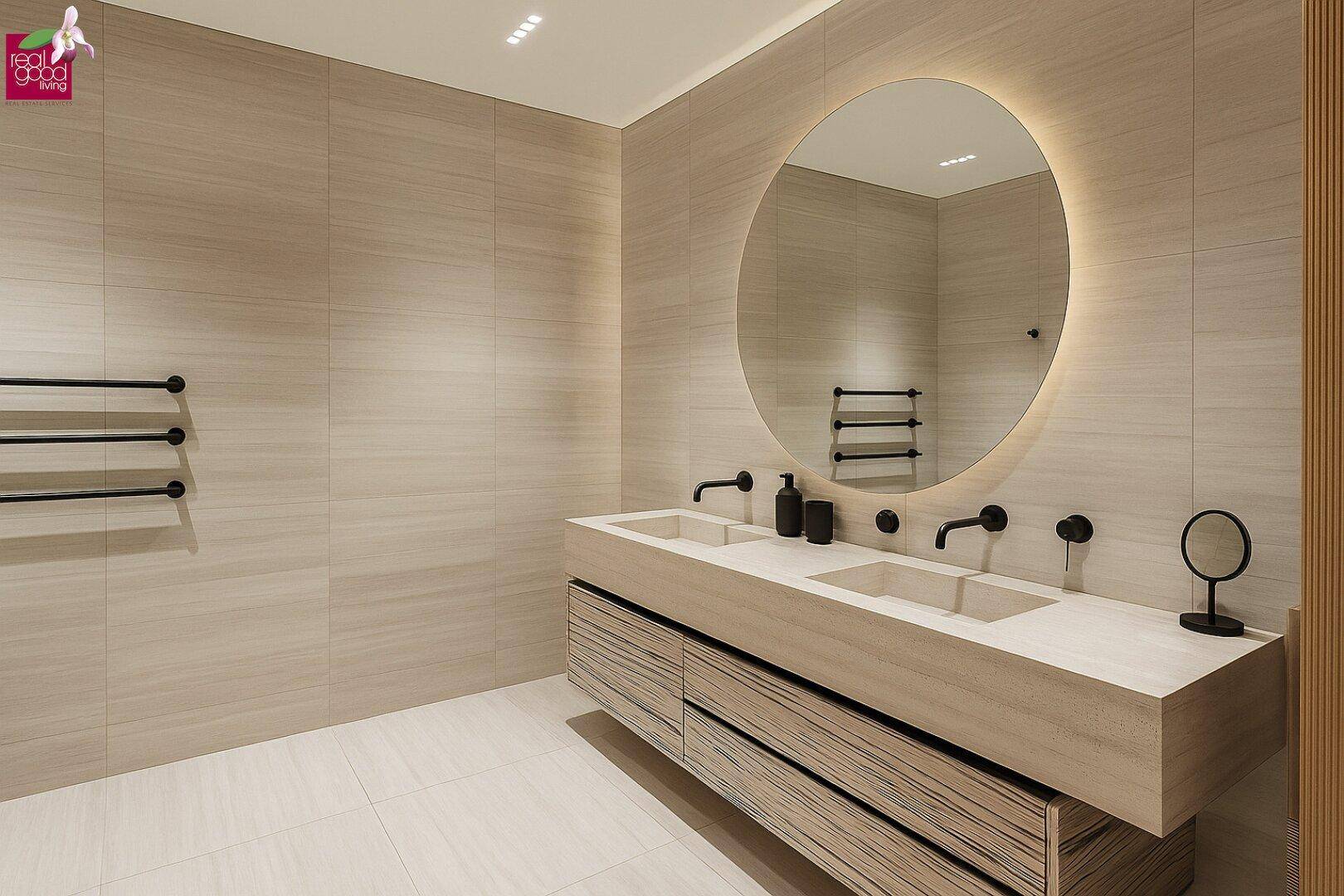 Modernes Badezimmer mit Doppelwaschbecken, beleuchtetem Spiegel und beigefarbenen Fliesen.
