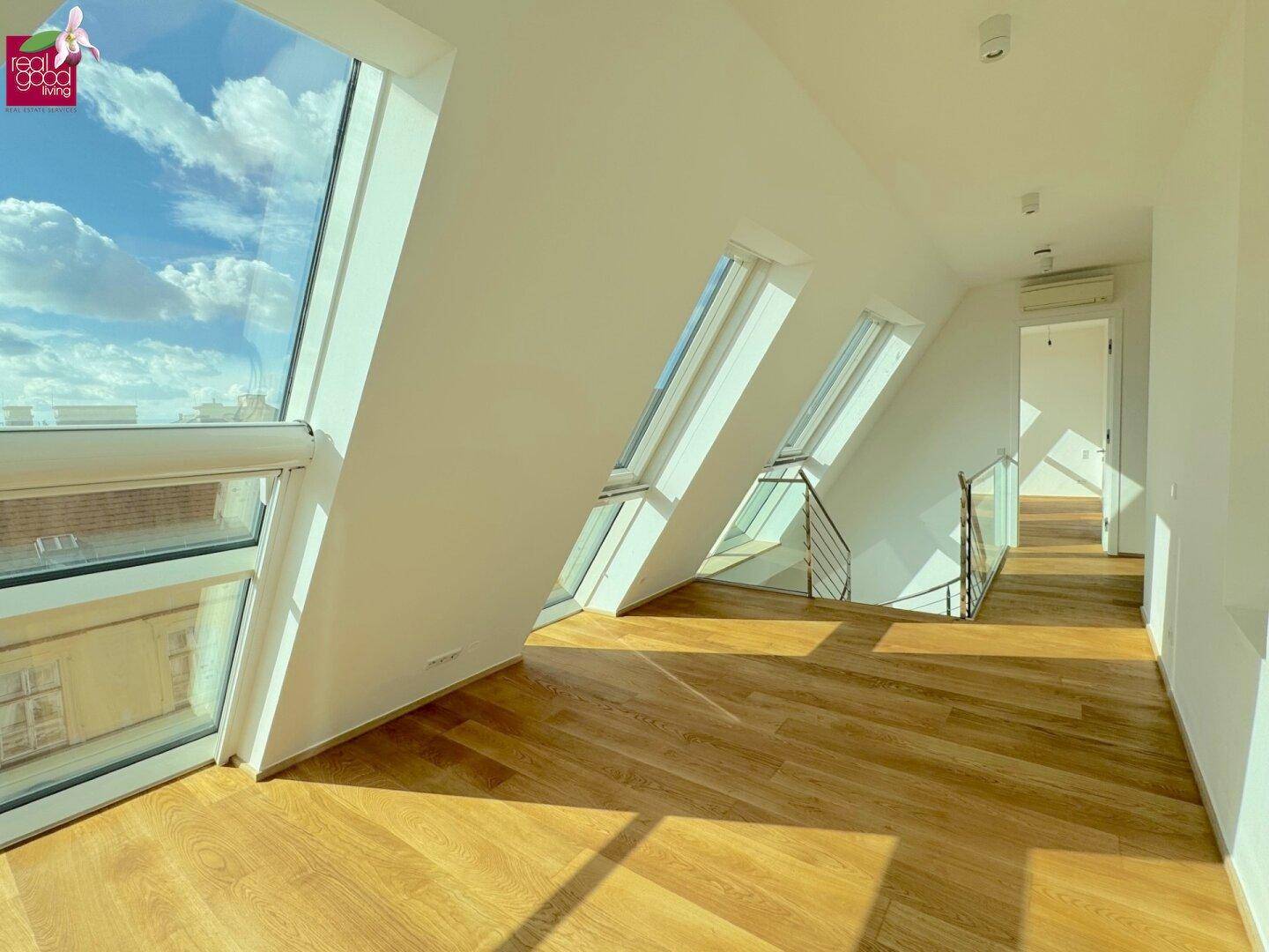 Heller Raum mit Holzboden, großen Dachfenstern und Blick in den Himmel, ideal für offenes Wohnen.