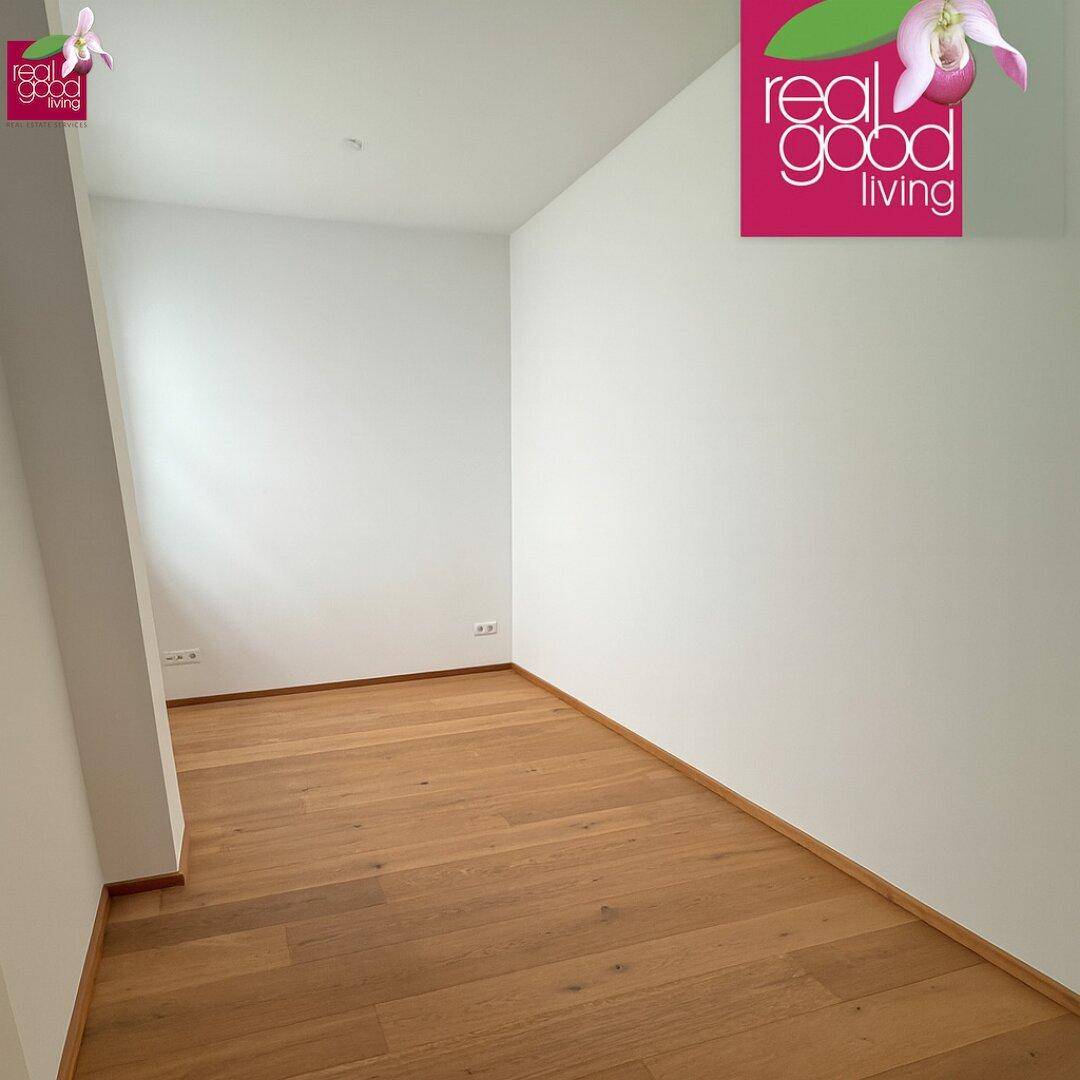 Leeres Zimmer mit hellem Holzfußboden und weißen Wänden, bereit zur Einrichtung.