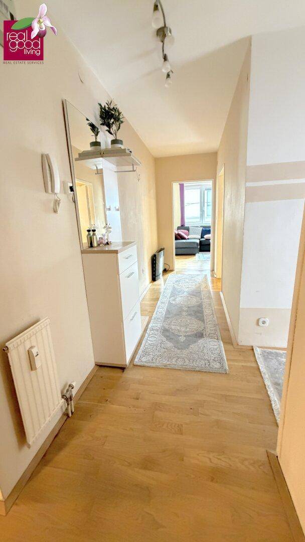 Heller Flur mit Holzfußboden, einem großen Spiegel und Blick in angrenzende Wohnbereiche.