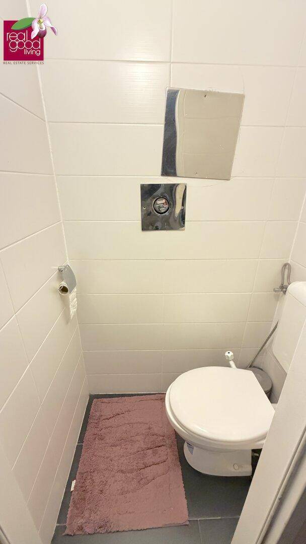 Separates WC mit Wand-WC und weißen Wandfliesen, ideal als Gästetoilette.
