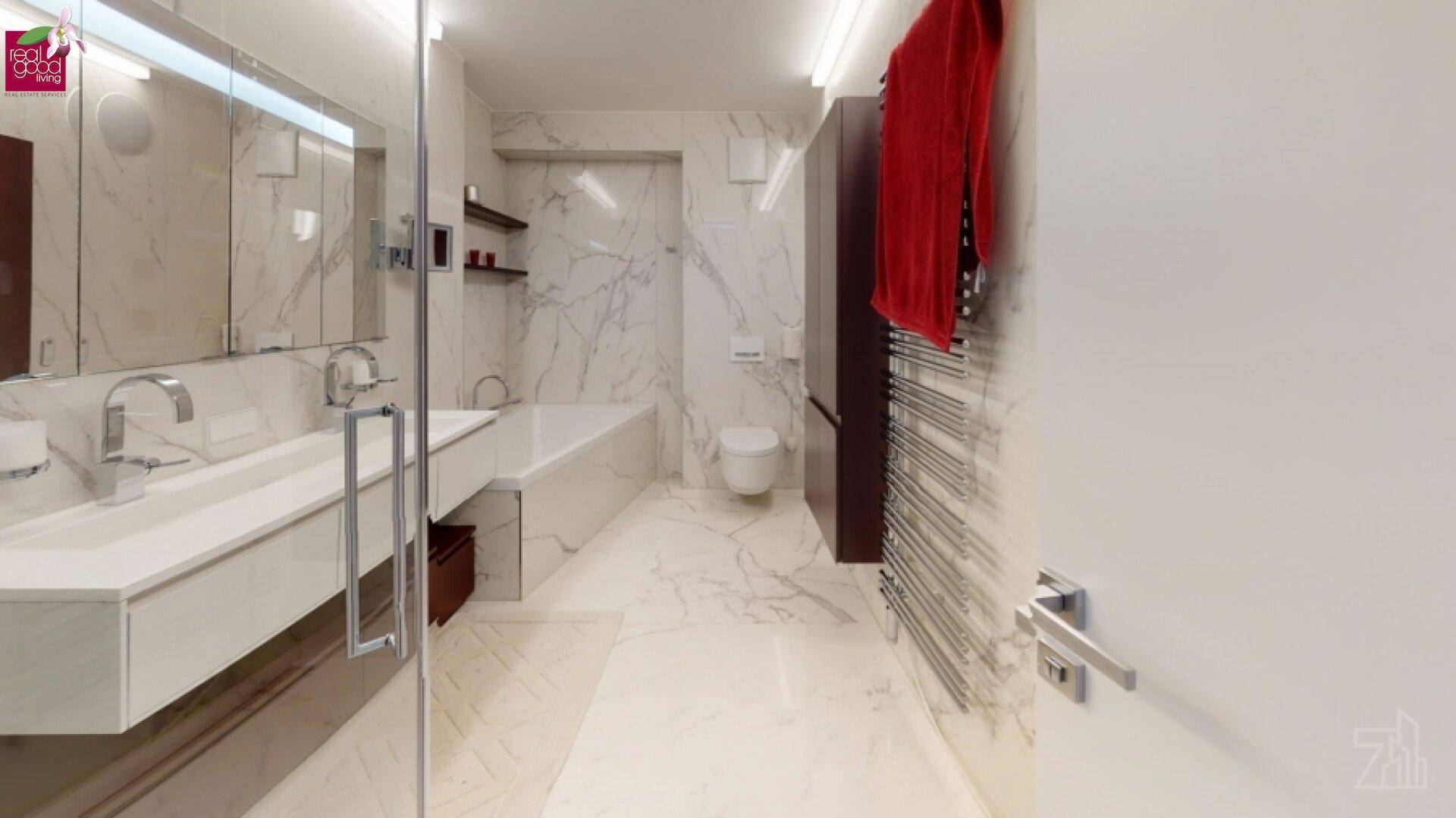 Elegantes Badezimmer mit Marmorfliesen, Doppelwaschbecken und integrierter Badewanne.