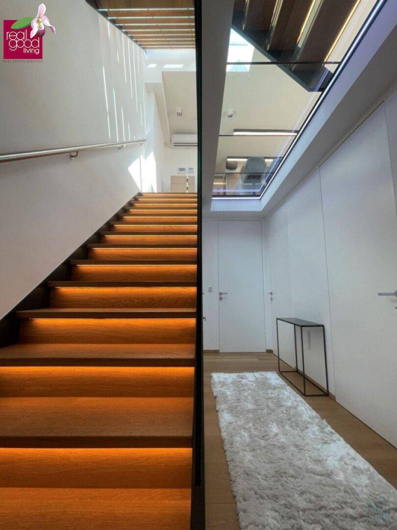 Moderne Treppe mit indirekter Beleuchtung und viel Tageslicht durch Oberlichter.